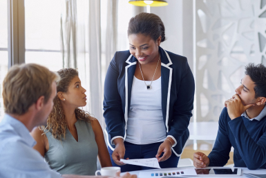 What-is-a-scrum-master-Scrum-master-jobs-and-career-paths Professionals meet at a conference table with a scrum master facilitating