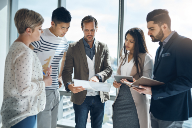 What-is-a-scrum-master-Scrum master responsibilities Four professionals gather in a stand up meeting in a sunny office