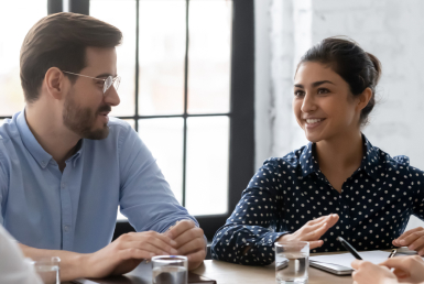what-is-a-scrum-master-section-1 Two colleagues converse at a conference table